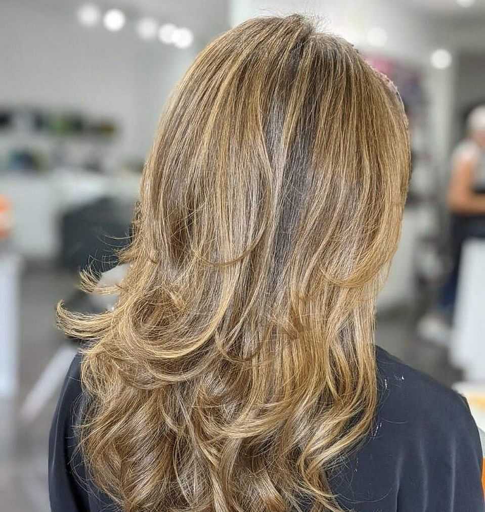 Golden blonde hair with layered curls in a salon setting.