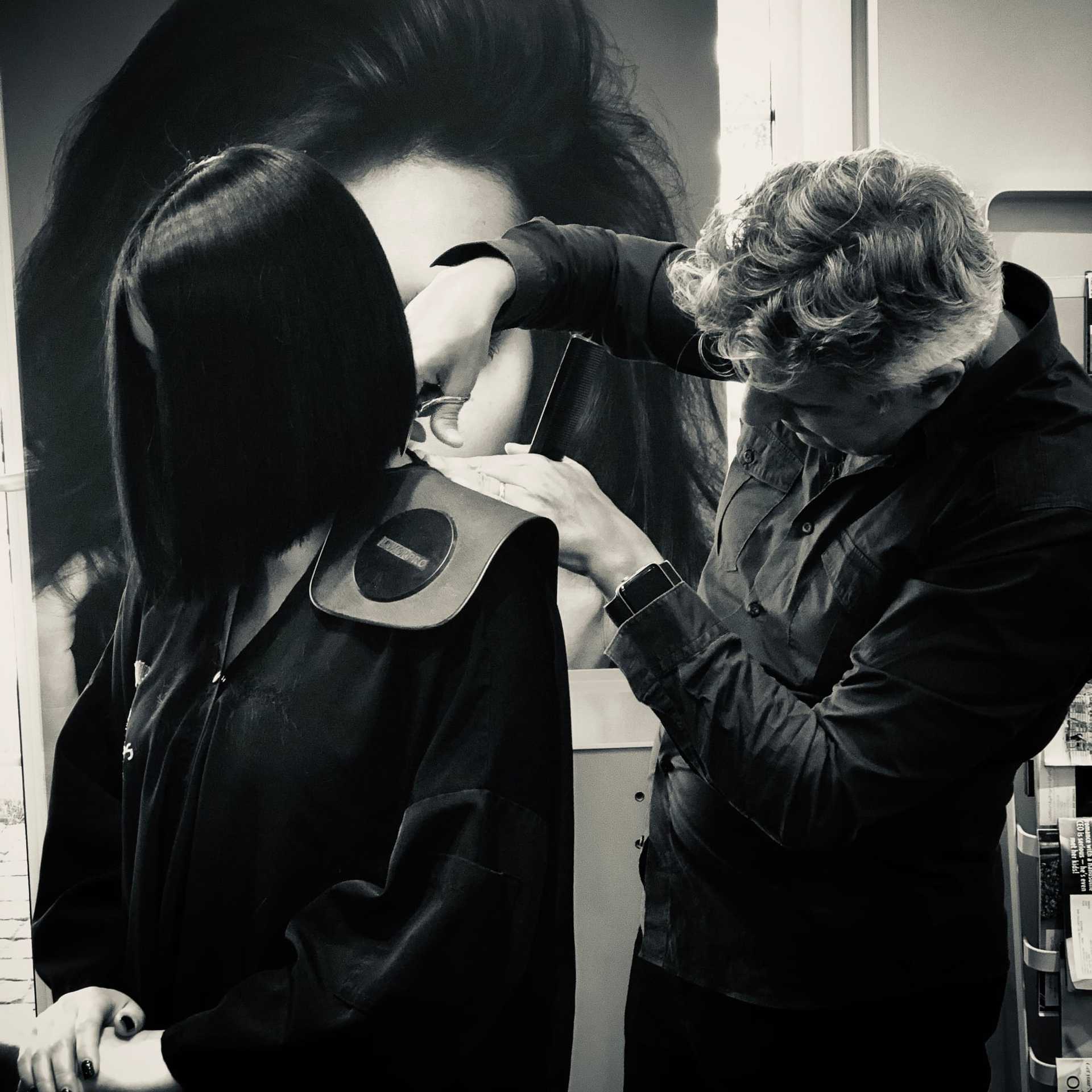 A stylist cuts a woman's hair in a salon, with a focus on precise technique.