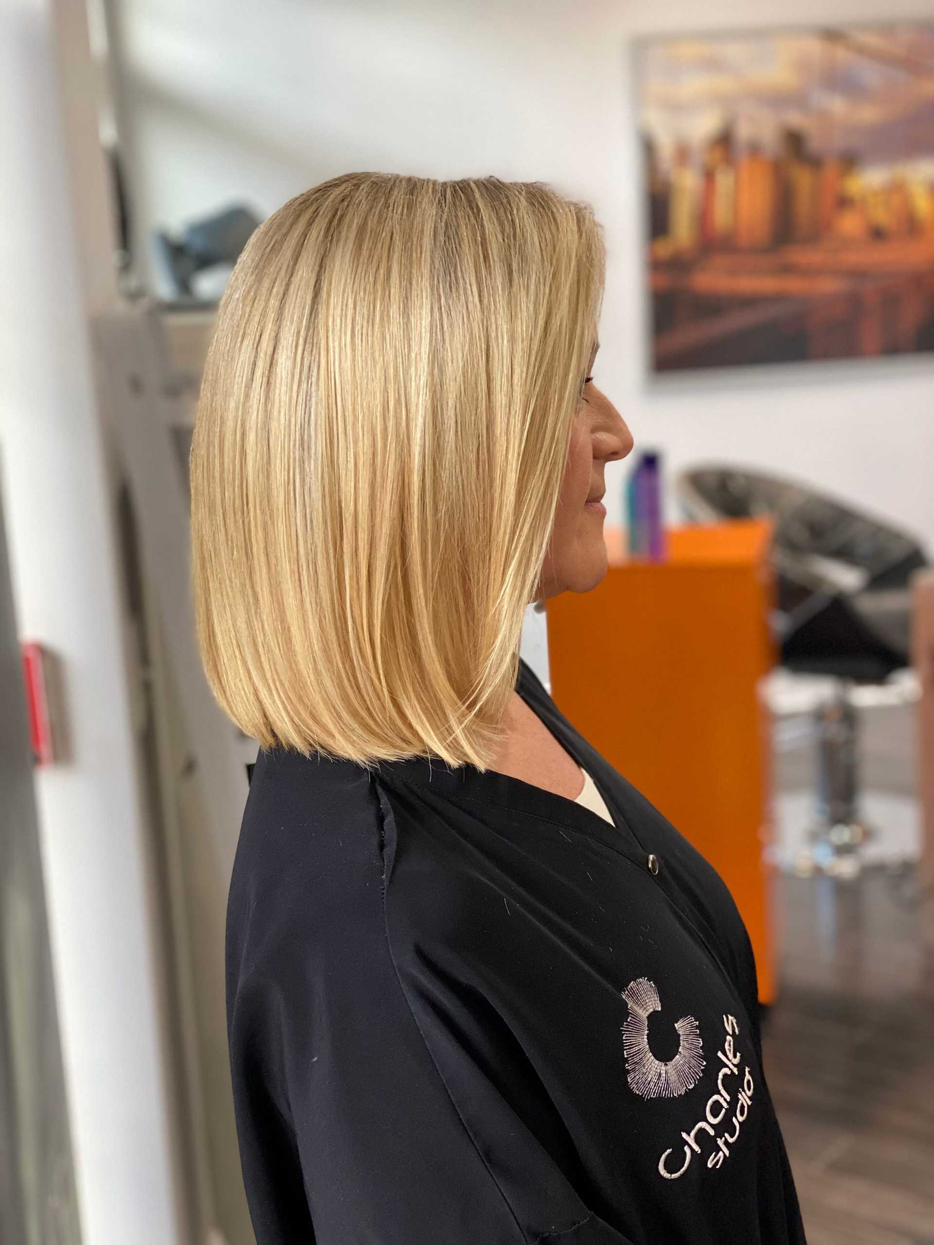 Woman with sleek, straight blonde bob haircut in a salon setting.