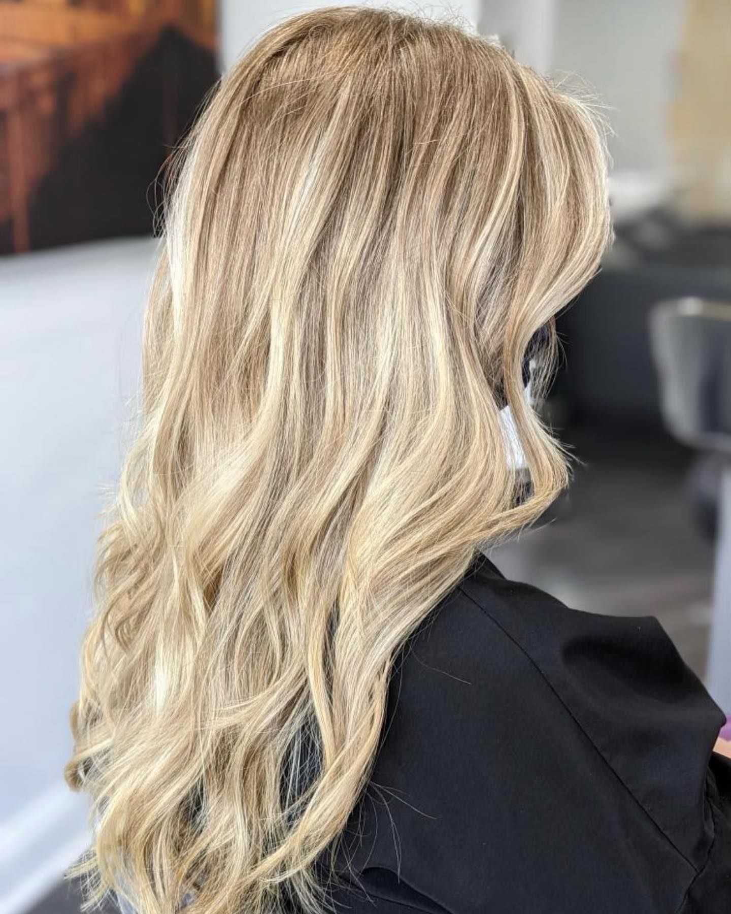 Blonde hair with soft waves viewed from behind in a salon setting.