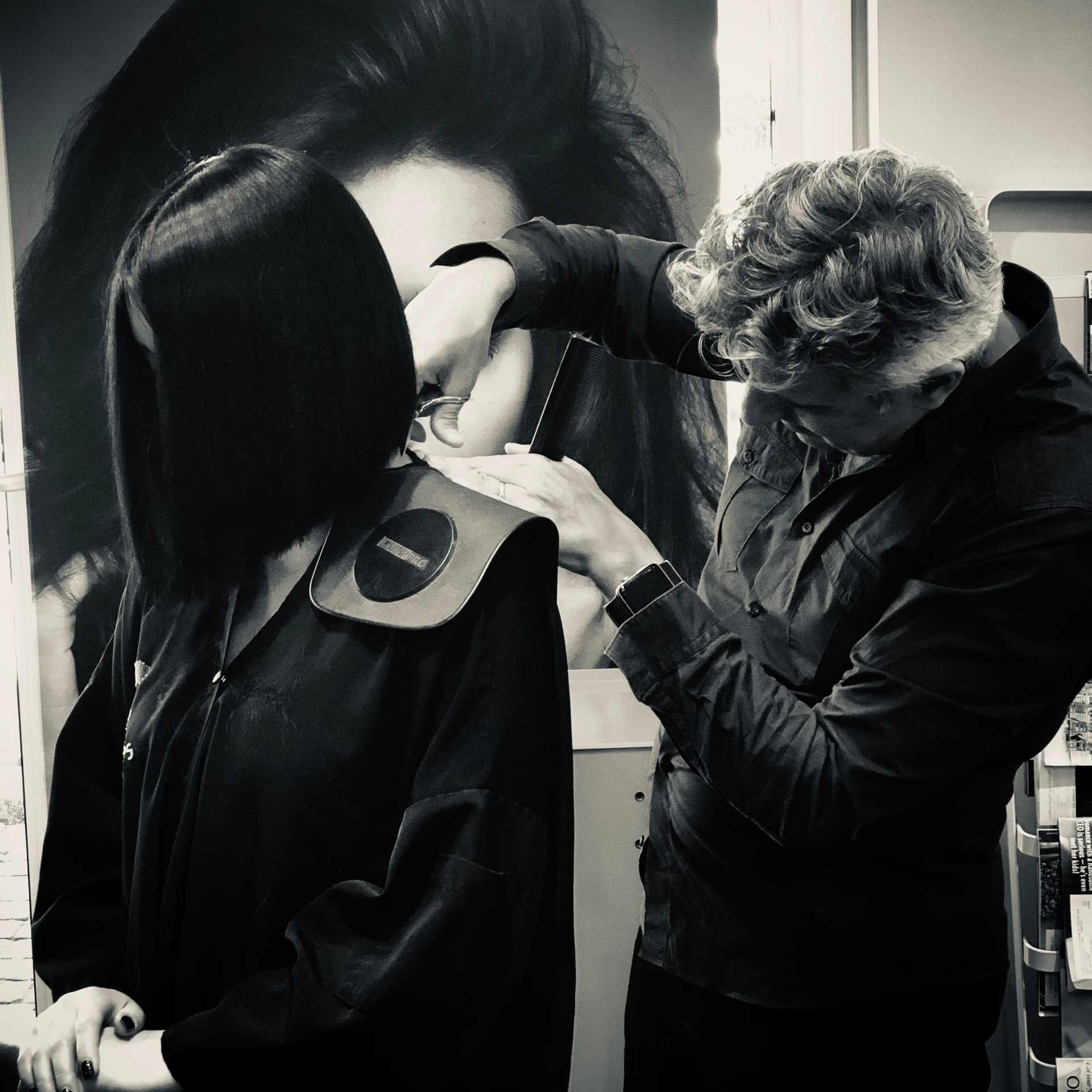 A stylist cuts a woman's hair in a salon, with a focus on precise technique.